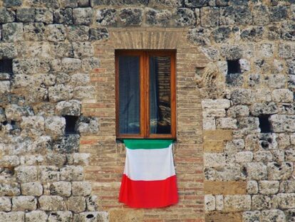 An italian flag on a window of an ancient brick building